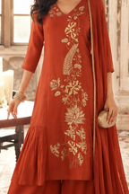 A woman models a rust-orange kurta suit with embroidery, featuring a matching dupatta 