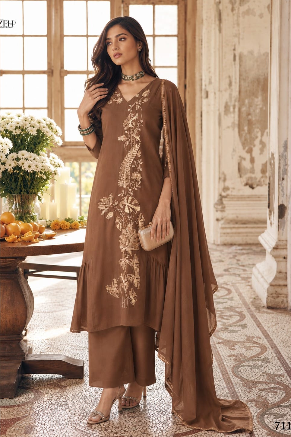 Woman wearing brown indian wedding guest dresses with an A-line pleated kurta, matching pant and net dupatta, gold zari and sequin work, full-length front view.