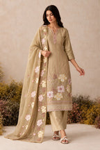 Woman wearing a camel beige kurta set in shimmer silk with floral thread embroidery, santoon pant and chiffon dupatta, full-length front view.