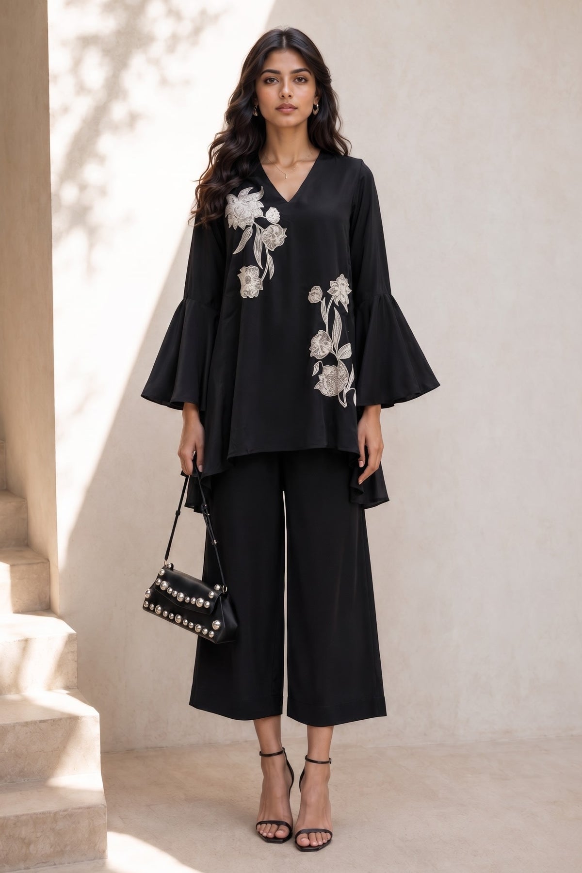 Full-length side view of a black diwali outfits for women co ord set, embroidered kurta with flared sleeves and wide-leg pant in natural crape.