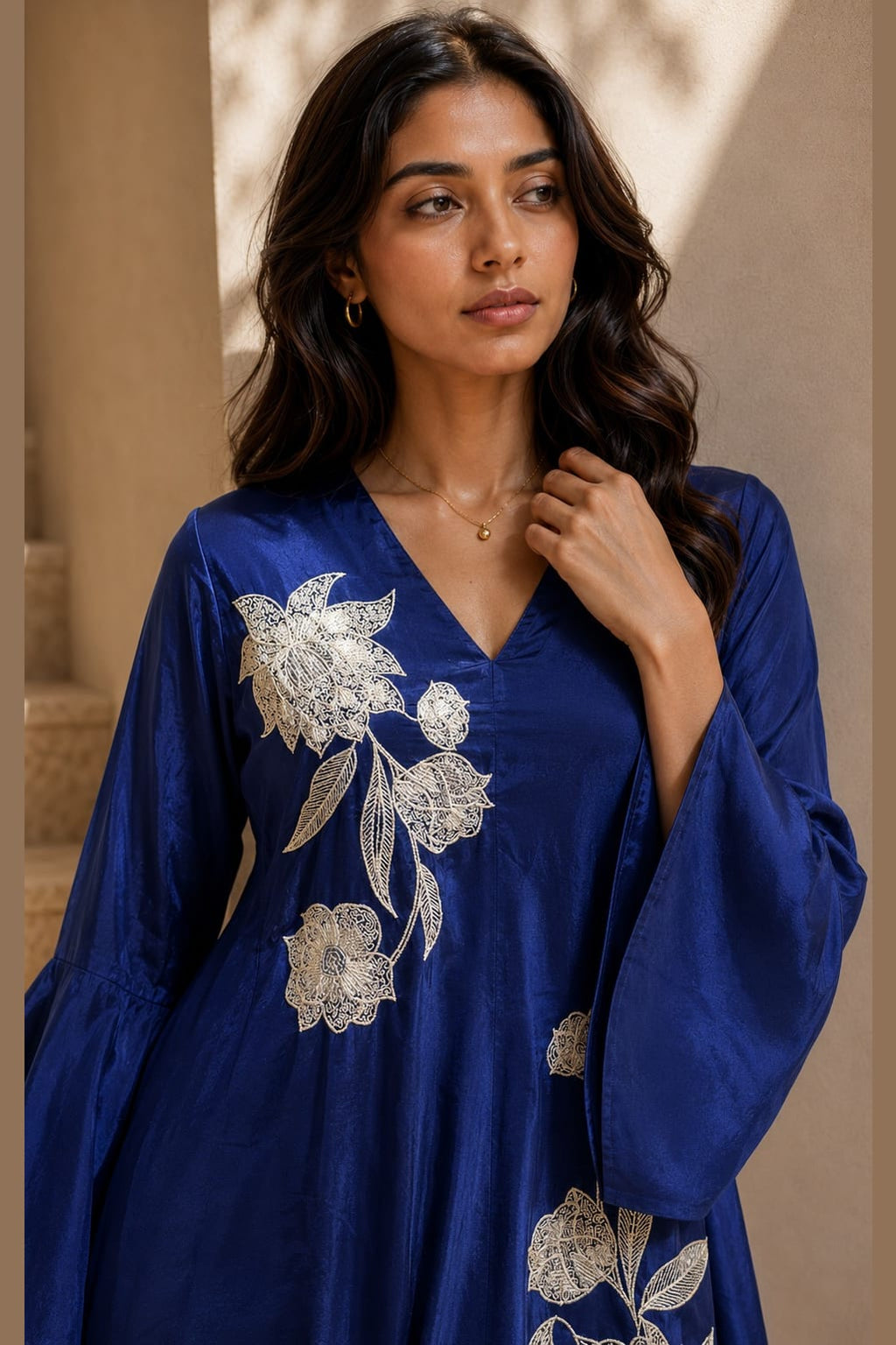 Close-up of a royal blue indian wedding guest dresses co ord set kurta with white floral embroidery on the V neckline and bell sleeves.