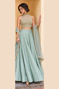 Woman wearing a pista green sangeet lehenga in roman silk with embroidered halter net choli and net dupatta, full-length front view.