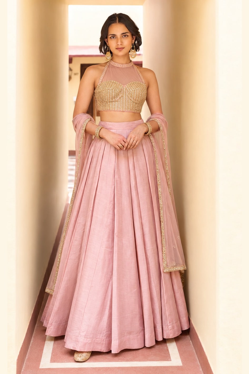 Woman wearing a light pink lehenga for wedding in roman silk with embroidered halter net choli and net dupatta, full-length front view.