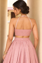 Waist-up back view of a light pink lehenga choli for women in roman silk with embroidered halter straps and plain skirt.