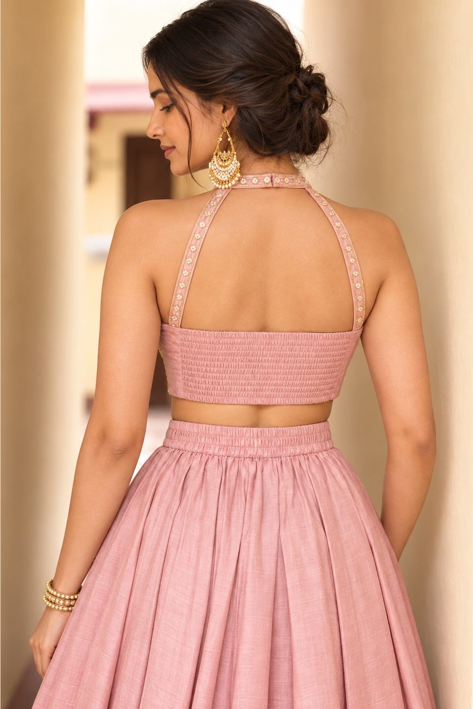 Waist-up back view of a light pink lehenga choli for women in roman silk with embroidered halter straps and plain skirt.