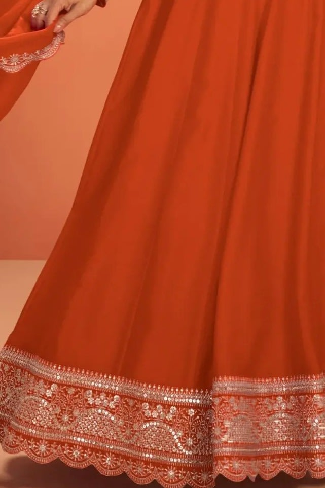 Waist-down detail view of a neon orange anarkali for wedding outfit in premium silk with sequin embroidered flared skirt hem.