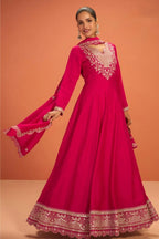 Woman wearing a pinkish red anarkali dress for wedding in premium silk with sequin and thread embroidery and silk dupatta, full-length front view.