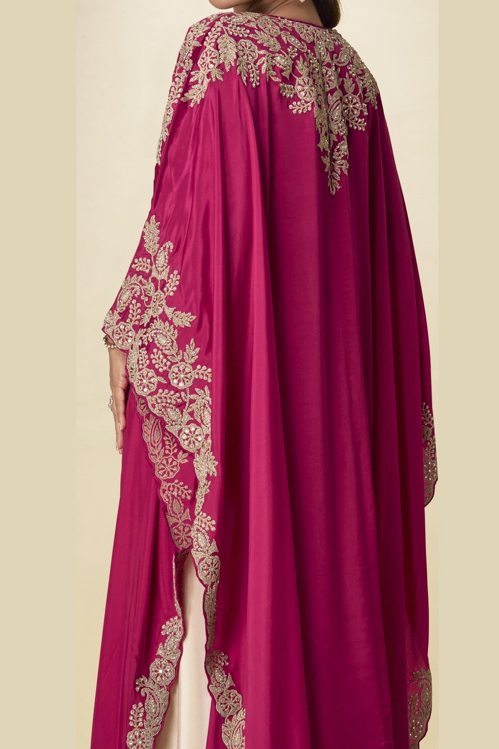 Back close-up view of a magenta palazzo salwar suit outfit showing detailed gold embroidery on the cape shoulders and flowing sleeves.