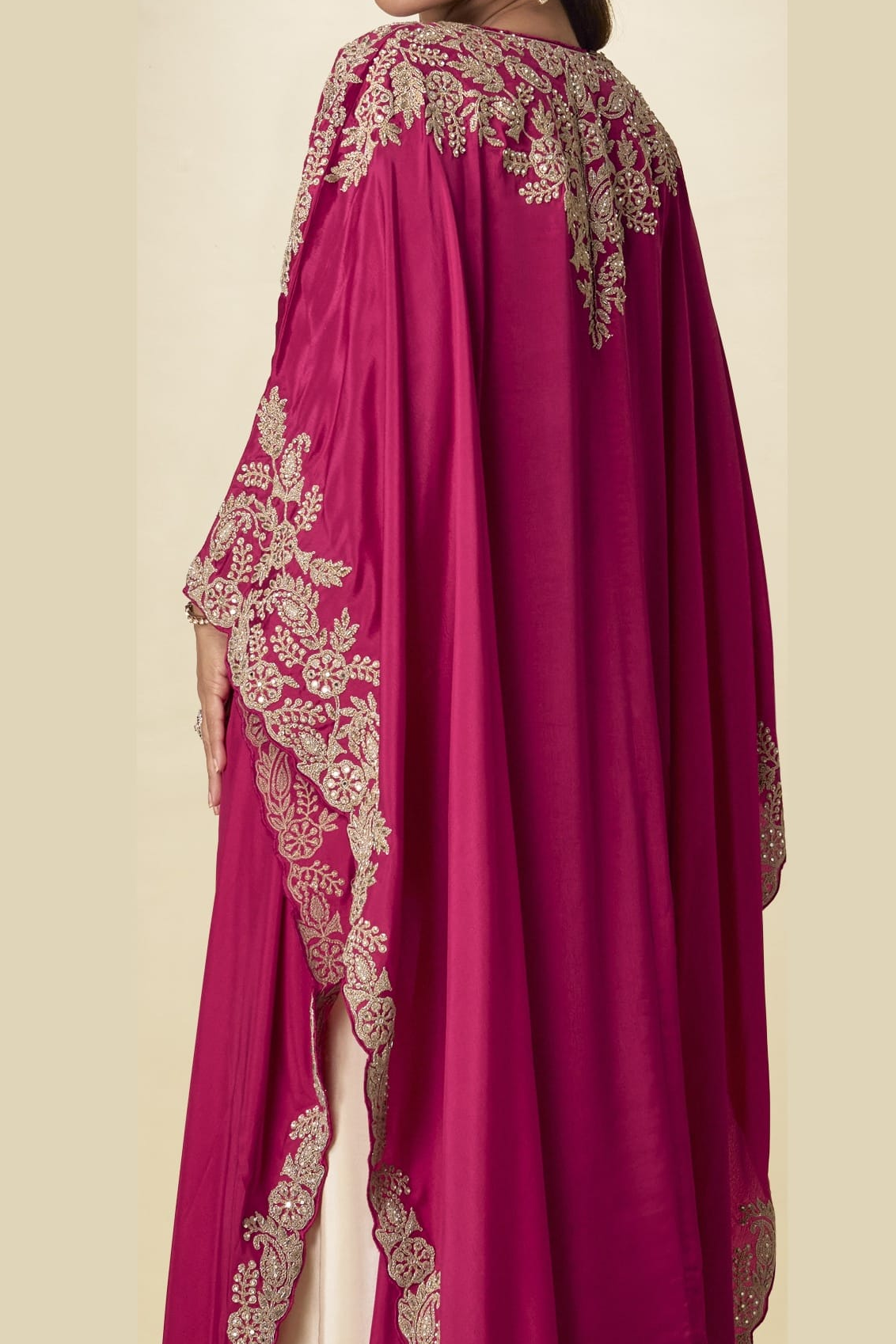 Back close-up view of a magenta palazzo salwar suit outfit showing detailed gold embroidery on the cape shoulders and flowing sleeves.