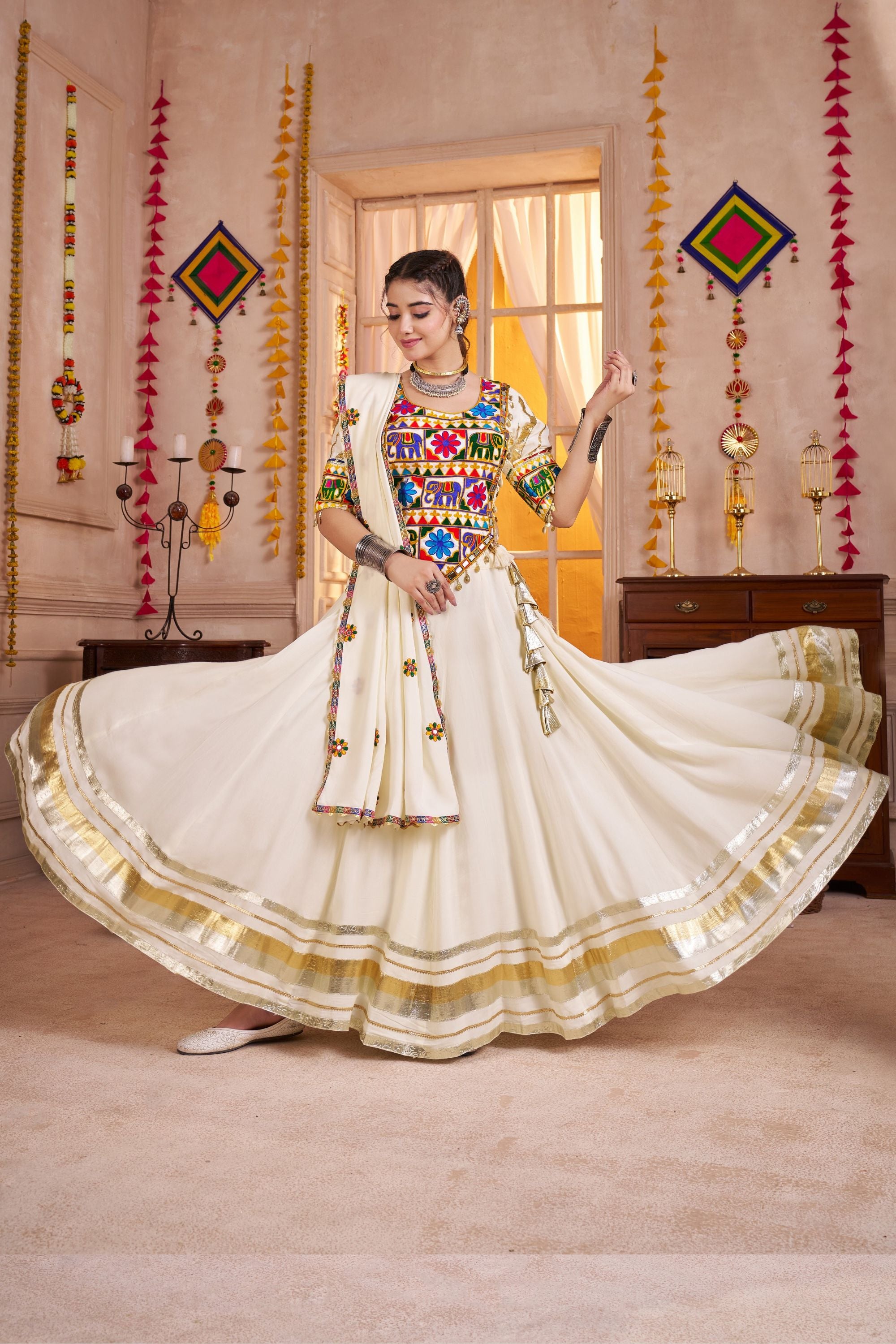 Woman in a traditional outfit with colorful top and white skirt in a decorated room.