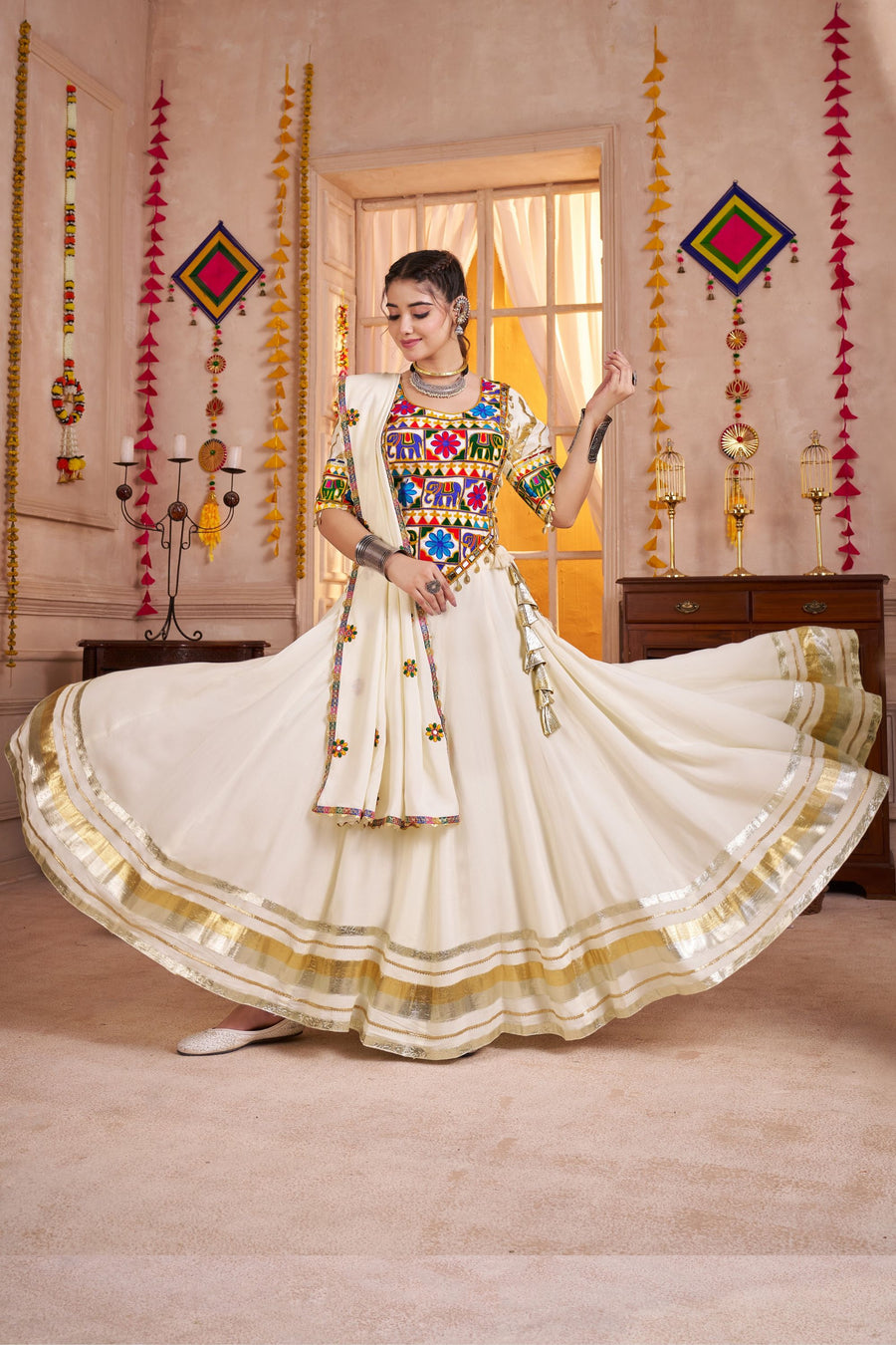 Woman in a traditional outfit with colorful top and white skirt in a decorated room.