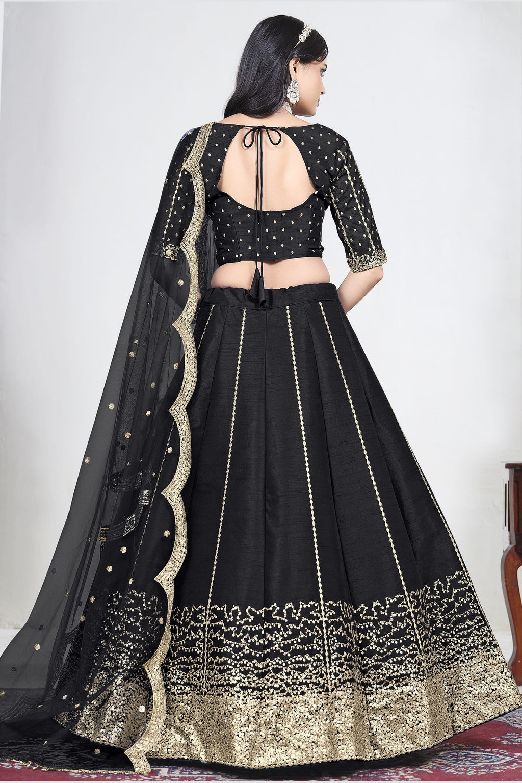 Full-length back view of a black wedding lehenga with an open back choli with dori tie and mirror work on the back. All-over mirror work.