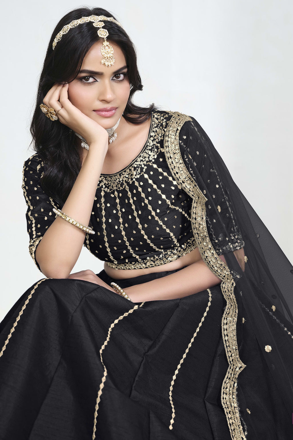 Close-up view of a black lehenga with mirror work showing detailed mirror, sequin and thread work on the art silk choli.