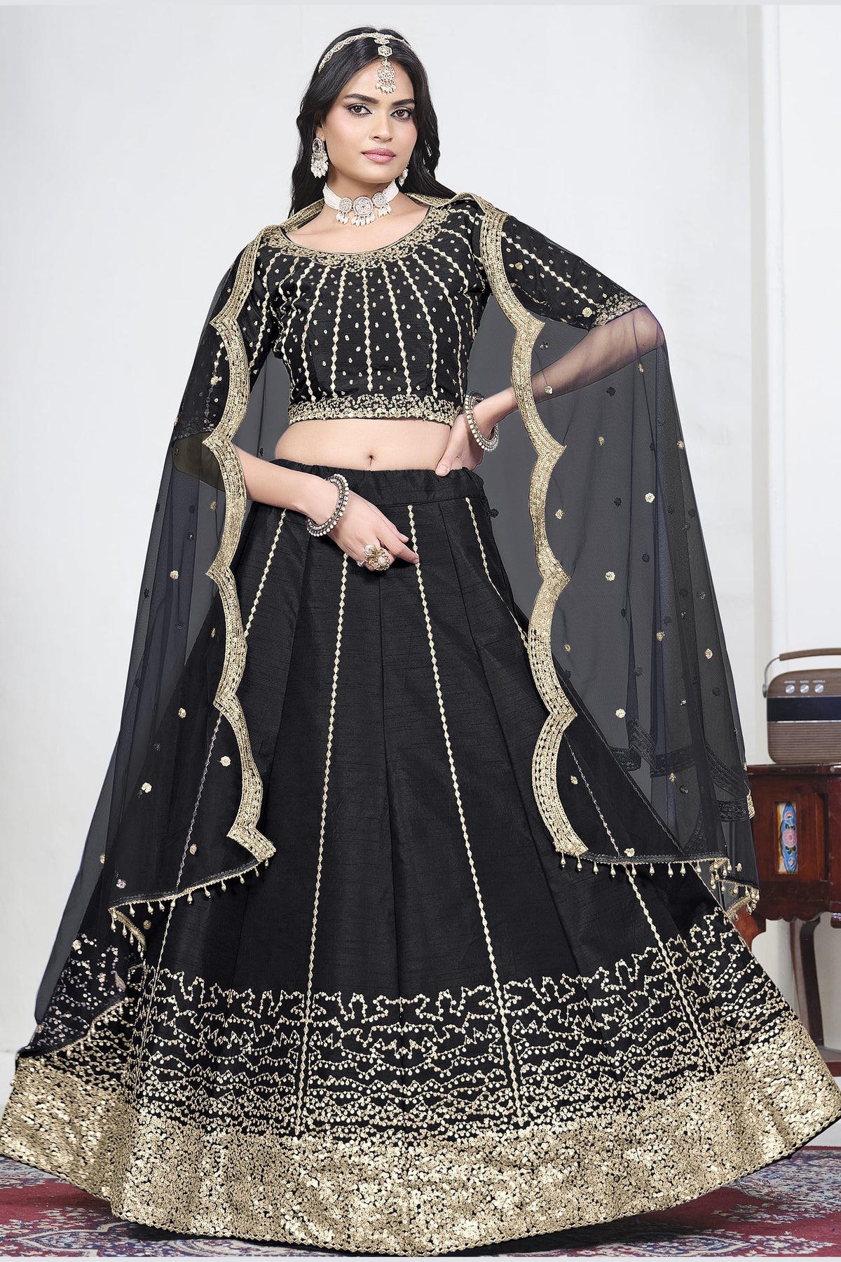 Woman wearing a black wedding lehenga with mirror work, half sleeve round neck art silk choli, full-length front view. All-over mirror work.