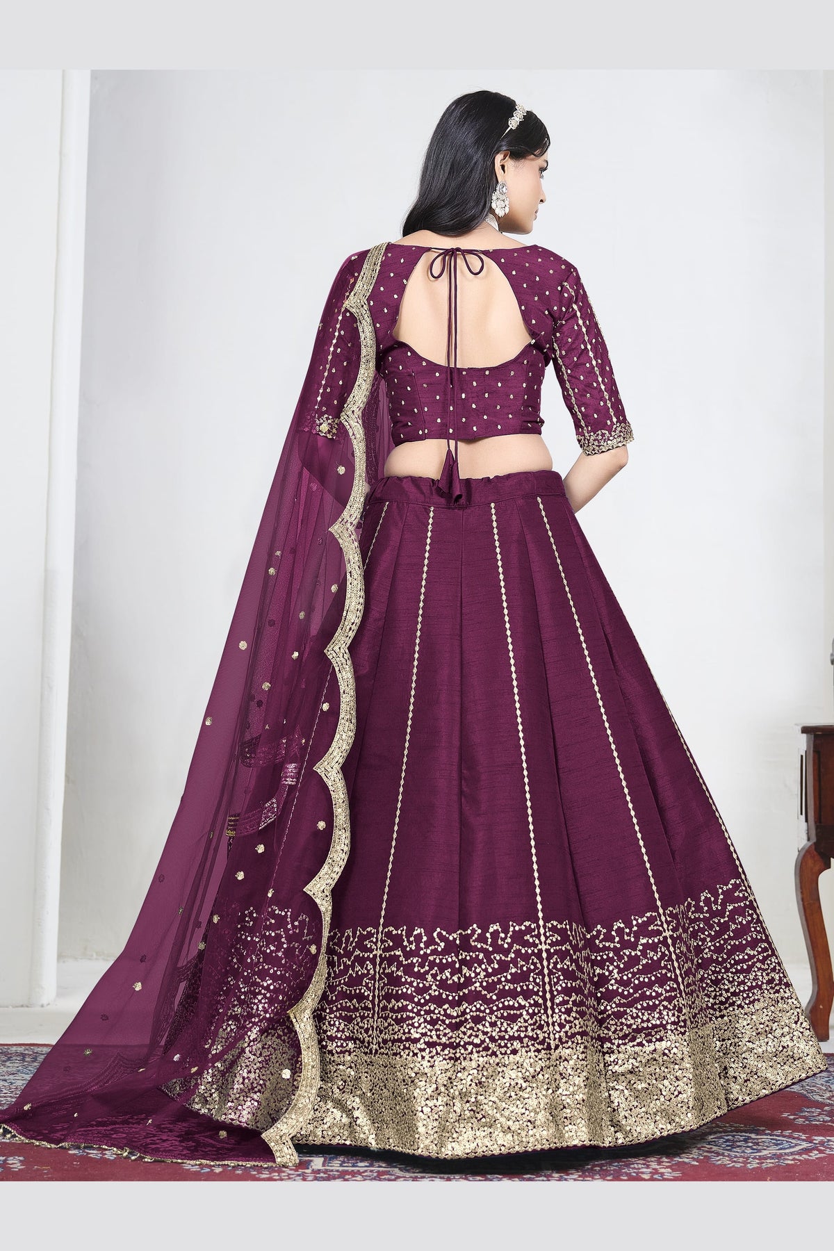 Full-length back view of a wine purple lehenga with mirror work with an open back choli with dori tie. All-over mirror work.