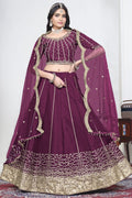 Woman wearing a wine purple lehenga with mirror work, half sleeve round neck art silk choli, full-length front view. All-over mirror work.