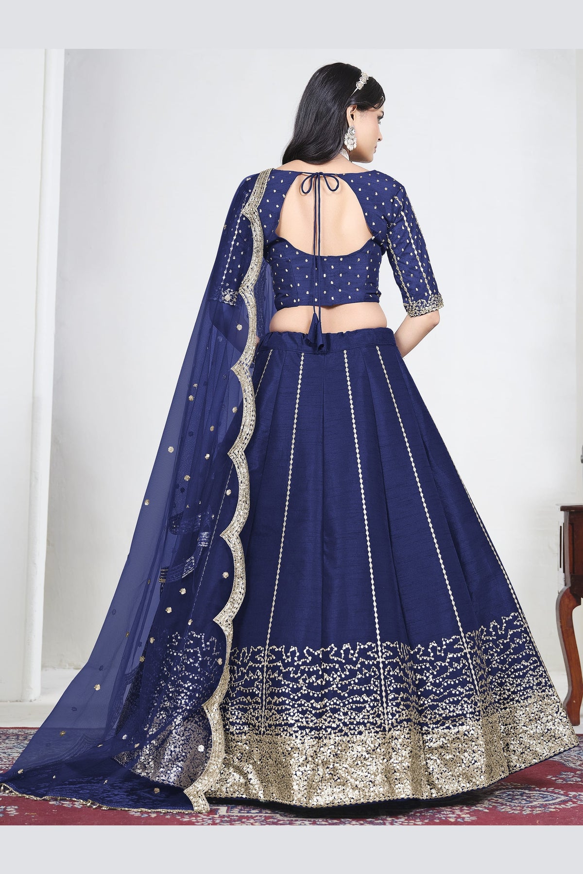 Full-length back view of a navy blue wedding lehenga with an open back choli with dori tie and mirror work. All-over mirror work.