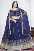 Woman wearing a navy blue lehenga skirt with mirror work, half sleeve round neck art silk choli, full-length front view.