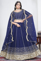 Woman wearing a navy blue lehenga skirt with mirror work, half sleeve round neck art silk choli, full-length front view.