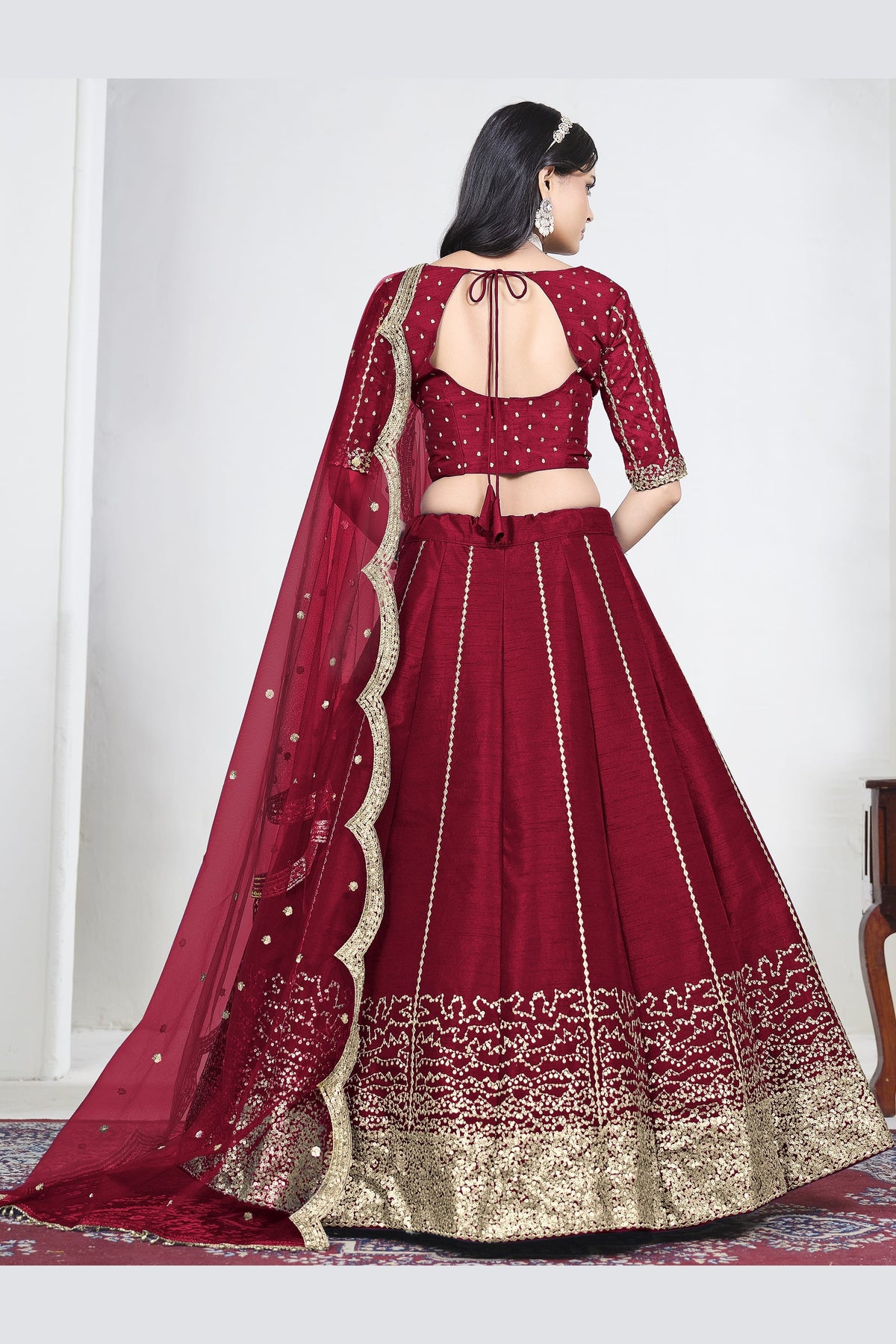 Full-length back view of a red wedding lehenga with an open back choli with dori tie and mirror work on the back. All-over mirror work.