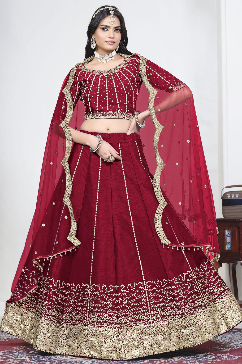 Woman wearing a red embroidered lehenga with mirror work, half sleeve round neck art silk choli, full-length front view.
