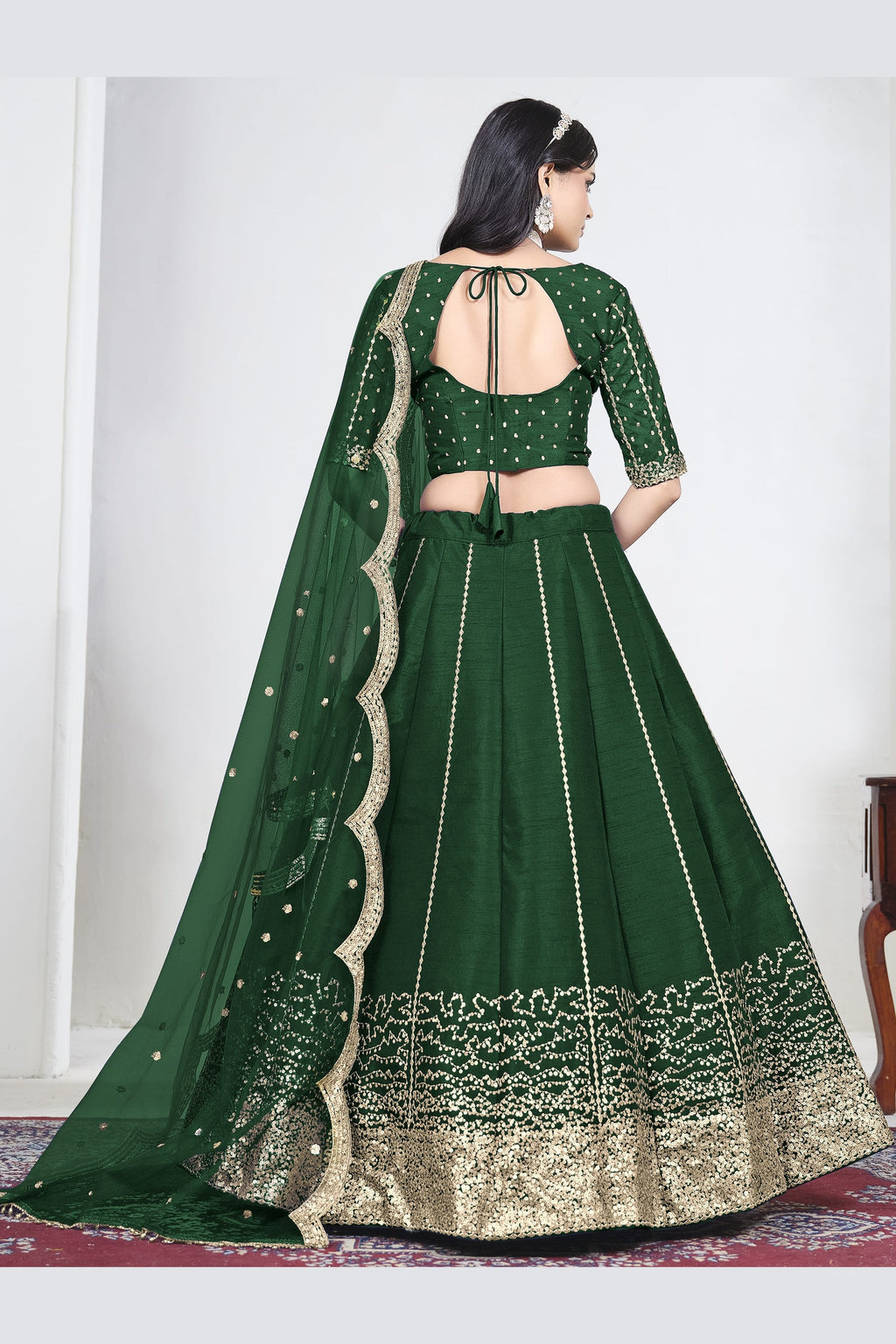 Full-length back view of a green wedding lehenga with an open back choli with dori tie and mirror work on the back. All-over mirror work.