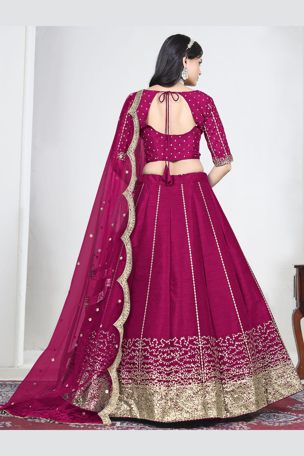 Full-length back view of a pink wedding lehenga with an open back choli with dori tie and mirror work on the back. All-over mirror work.