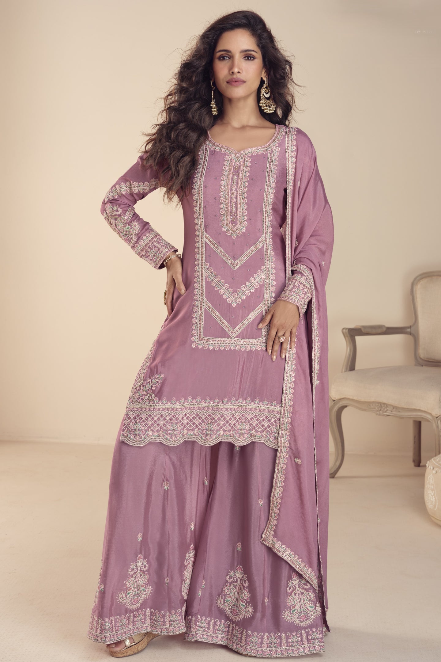 Woman wearing a lilac embroidered traditional outfit in a neutral setting