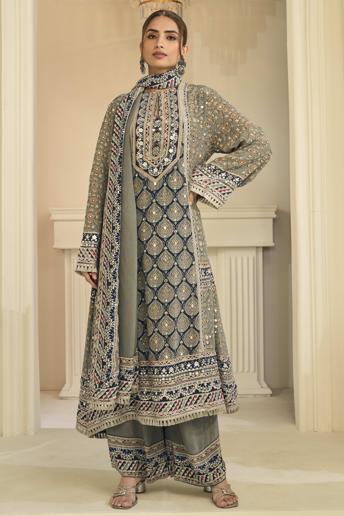 Woman wearing greenish grey indian wedding guest dresses style plazo suit in crepe silk with hand aari work and gota patti work, printed plazo and dupatta, full-length front view.