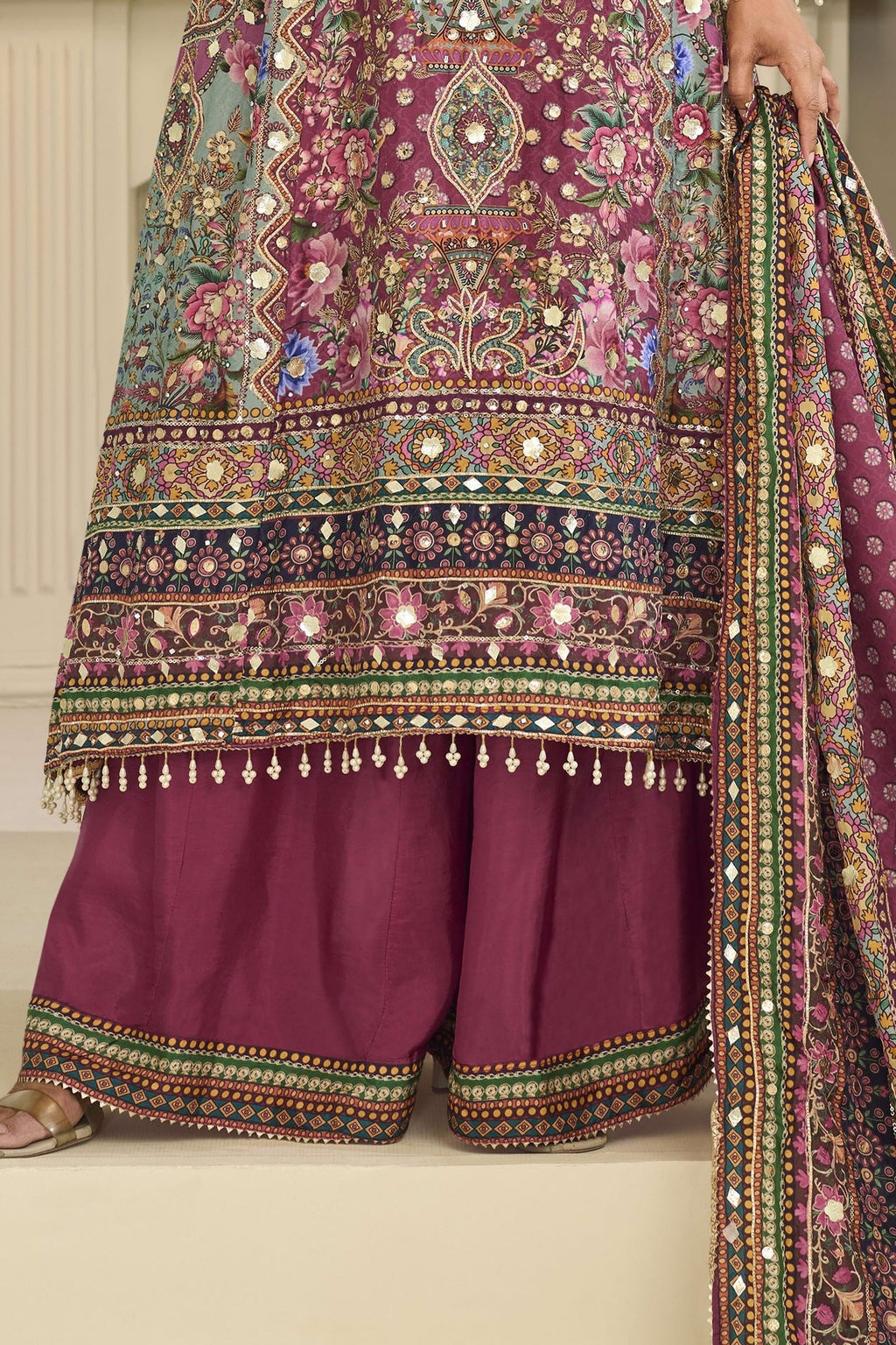 Lower-body detail of a maroon festive wear for women plazo suit in crepe silk with hand aari work and gota patti work on the kameez hem and printed plazo.