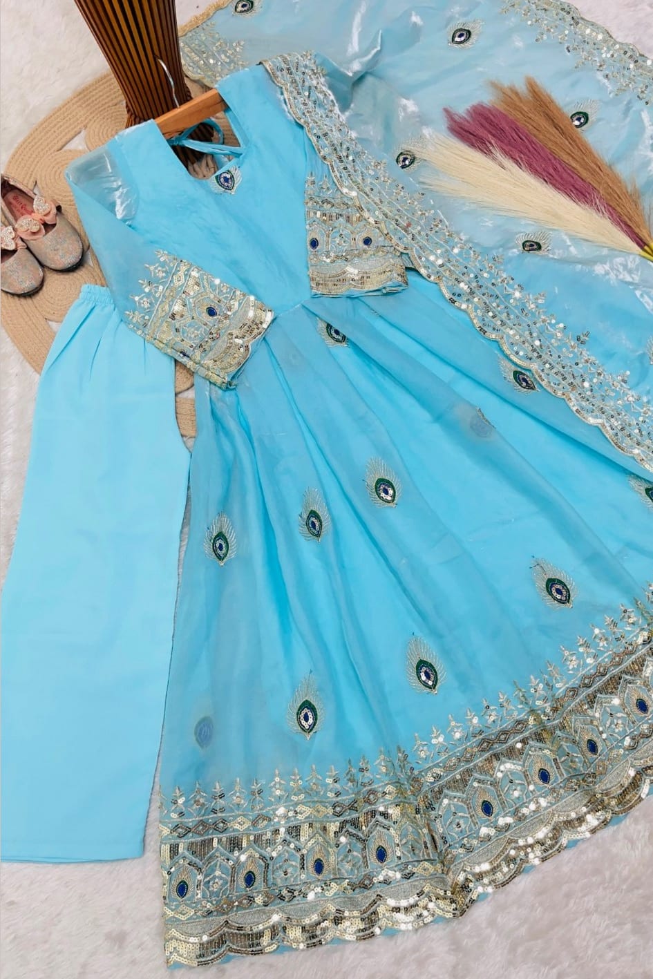 Close-up of white childrens indian costume anarkali top showing peacock feather embroidery with zari and sequin work.