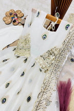 Close-up of white childrens indian outfits anarkali top showing peacock feather embroidery with zari and sequin work.