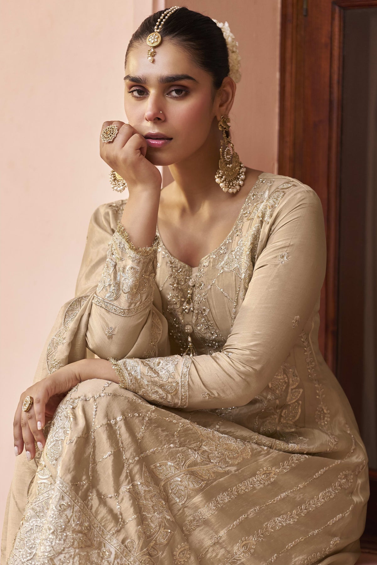 Seated model in a beige palazzo suit for women, displaying the embroidered kurta front and flowing simmer silk dupatta.