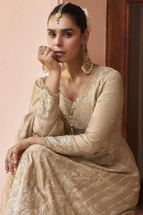 Seated model in a beige palazzo suit for women, displaying the embroidered kurta front and flowing simmer silk dupatta.
