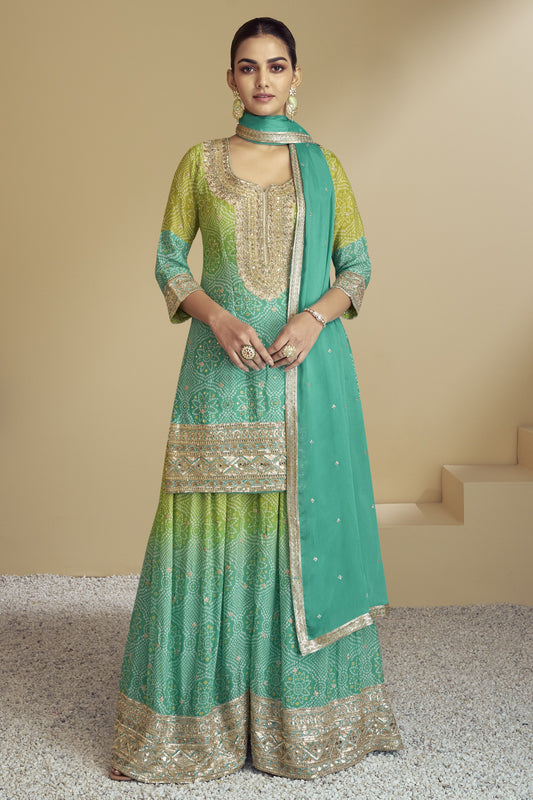 A woman wearing a green and beige chinon silk bandhani style palazzo suit with embroidery work and a dupatta.