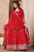 Woman wearing red indian wedding guest dresses style anarkali suit in art silk with sequin and thread embroidery, crepe churidar and embroidered dupatta, full-length front view.