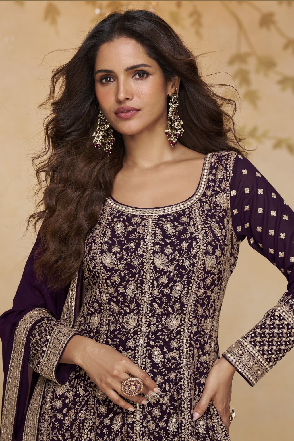 Close-up front view of a purple anarkali suit for wedding in georgette with gold zari floral embroidery, round neckline and embroidered full sleeves.