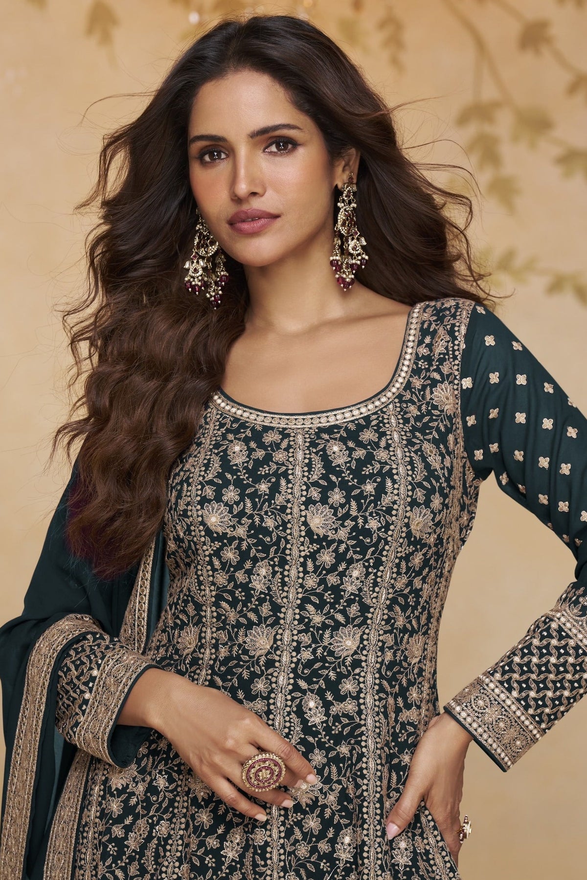 Close-up front view of a teal anarkali suit for wedding in georgette with gold zari floral embroidery, round neckline and embroidered full sleeves.