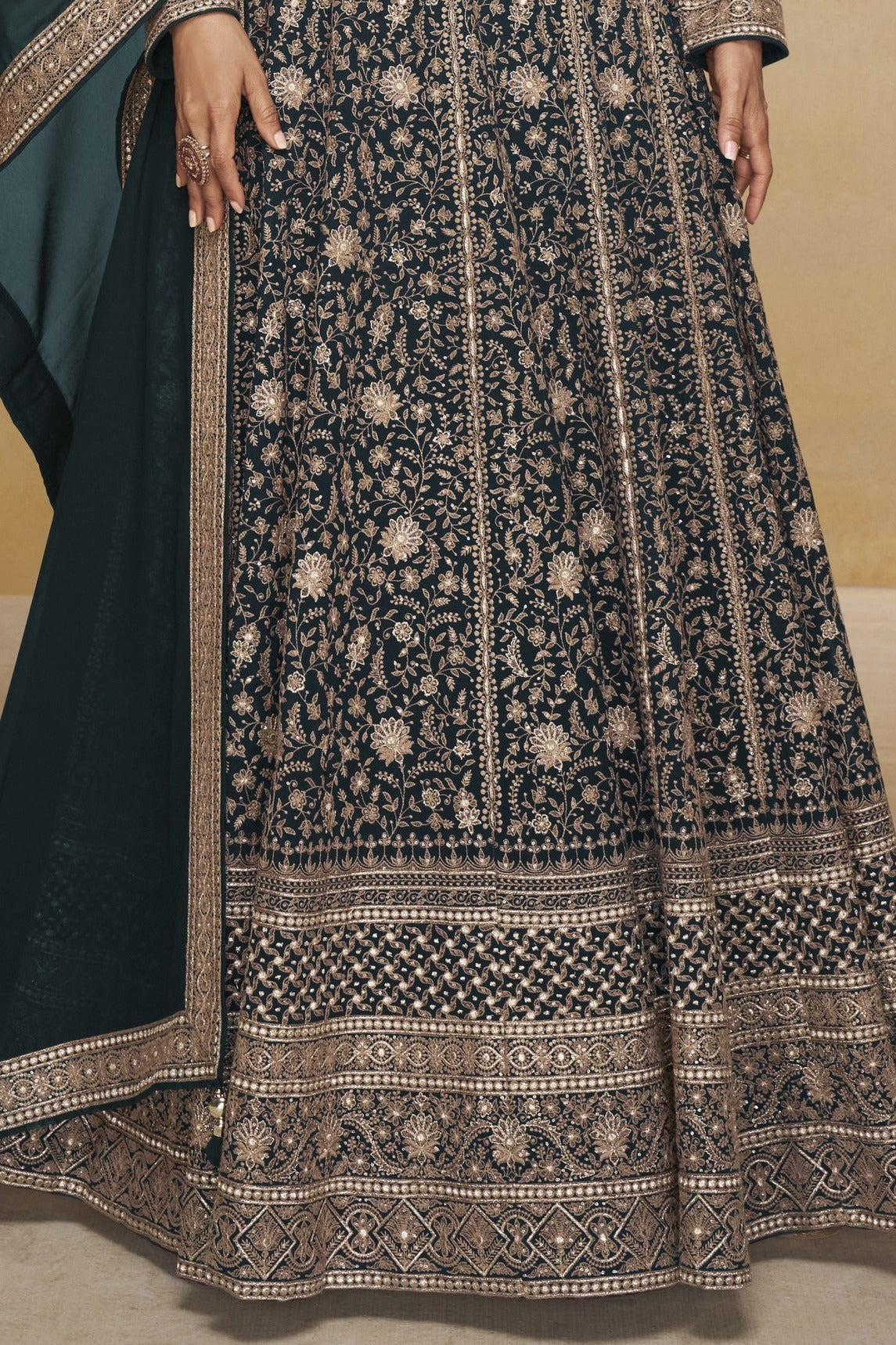 Waist-to-hem view of a teal pakistani anarkali suit in georgette with gold zari floral embroidery and wide embroidered hem border.