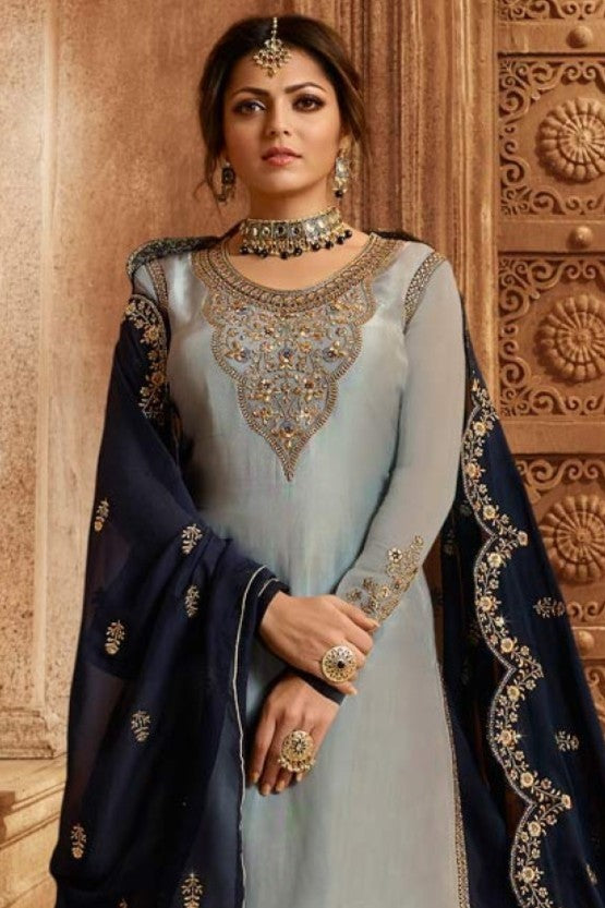 A waist-up front view of a woman wearing a light gray pakistani kameez with an embroidered round neckline and navy dupatta.