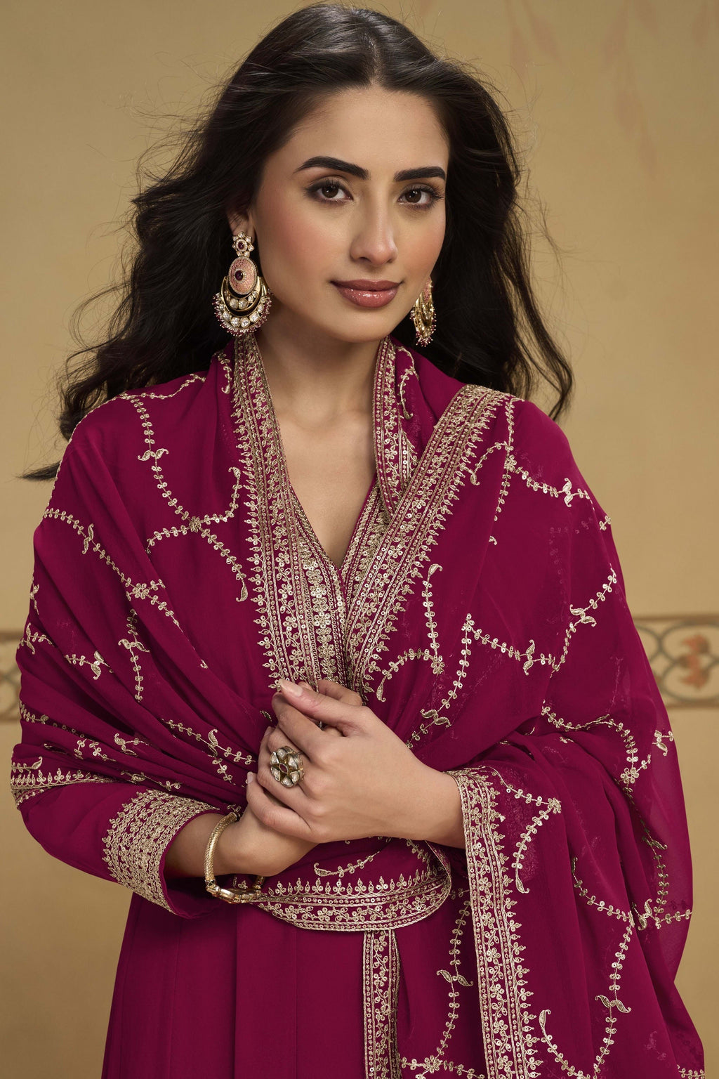 Close-up front view of a reddish pink pakistani suits style kurta in georgette with thread and sequin embroidered neckline and dupatta border.