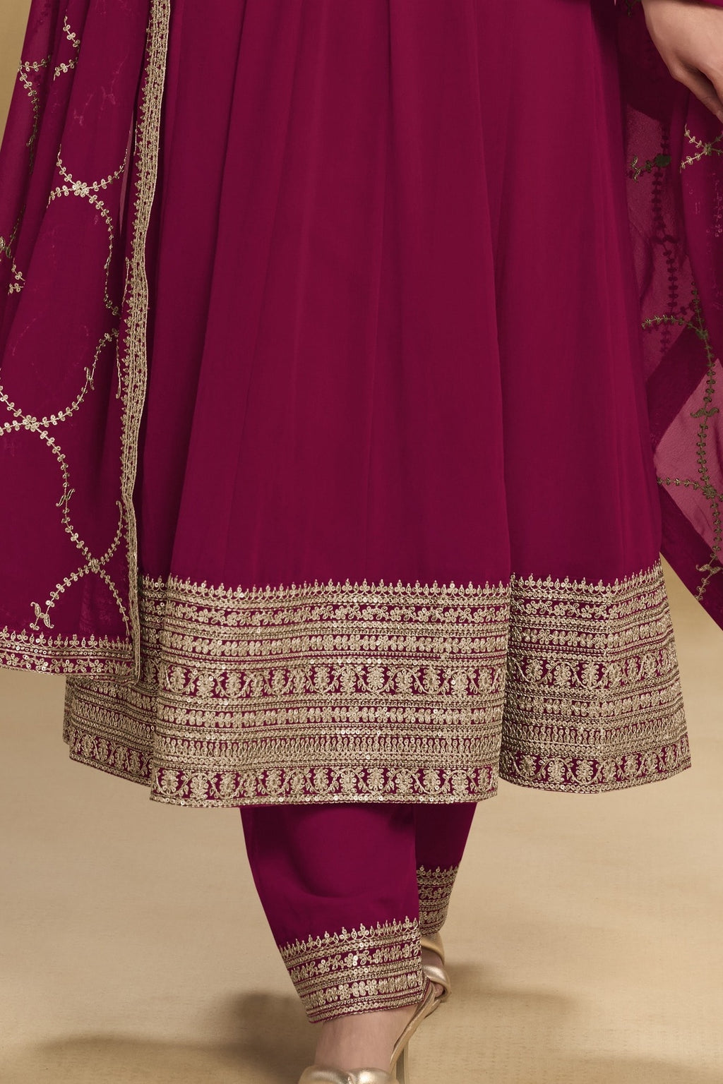 Waist-down detail view of a reddish pink wedding salwar kameez in georgette with thread and sequin embroidery on the kurta hem and pant.