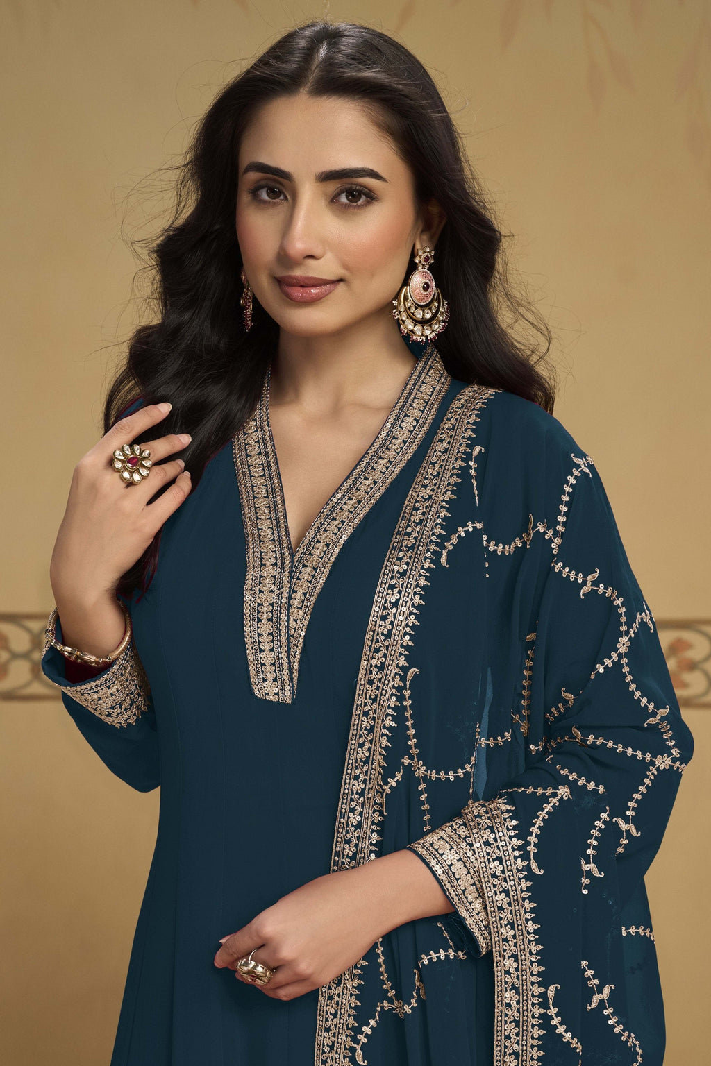 Woman wearing a dark teal kurta set in georgette with thread and sequin embroidery, georgette pant and dupatta, full-length front view.
