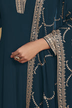 Waist-down detail view of a dark teal party wear salwar kameez in georgette with thread and sequin embroidery on kurta hem and pant.