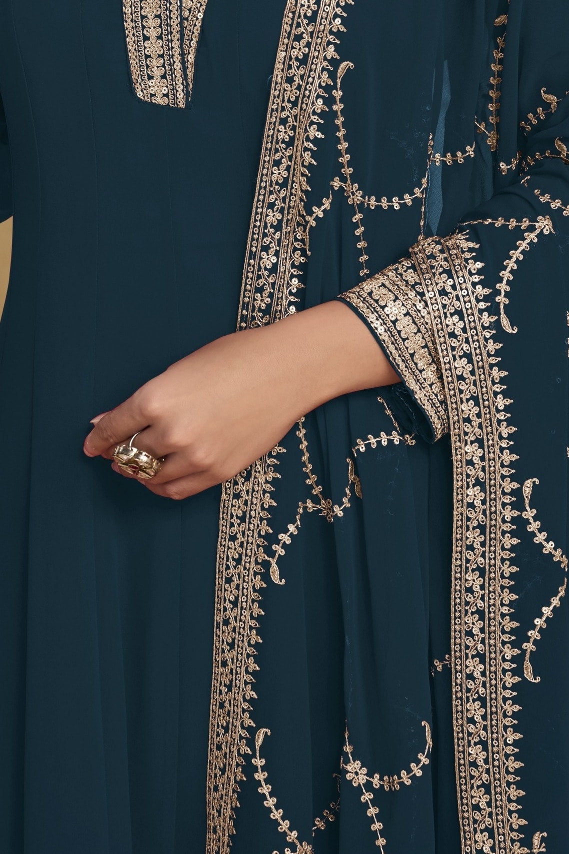 Waist-down detail view of a dark teal party wear salwar kameez in georgette with thread and sequin embroidery on kurta hem and pant.