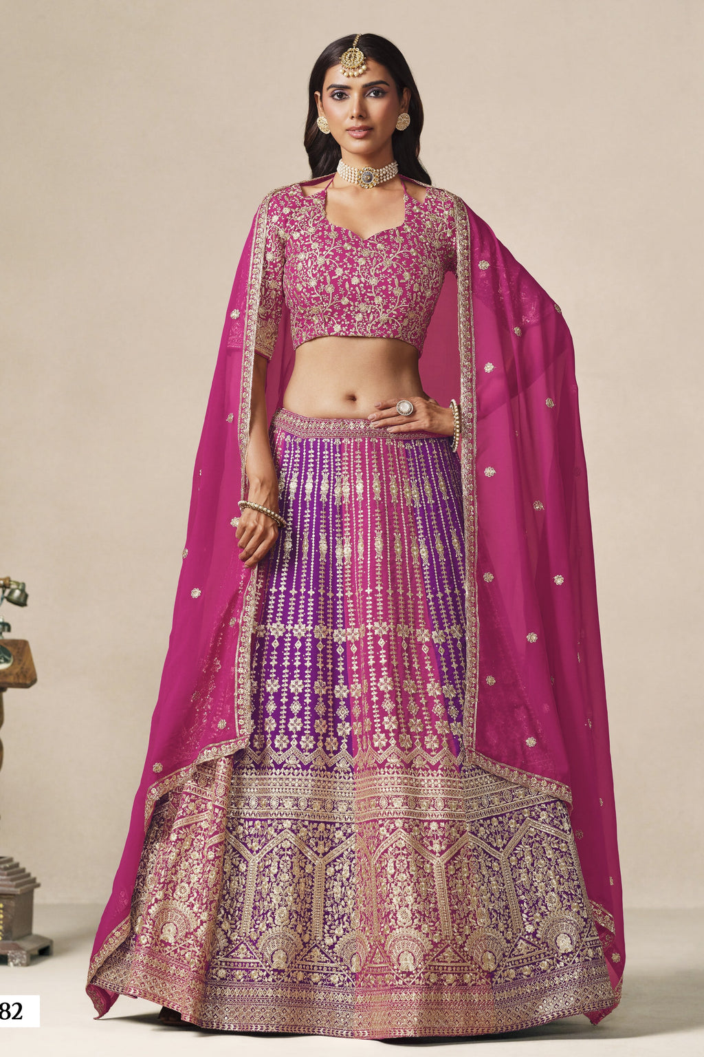 Woman wearing a magenta lehenga for sangeet in georgette with zari and sequin work, embroidered blouse and dupatta, full-length front view.