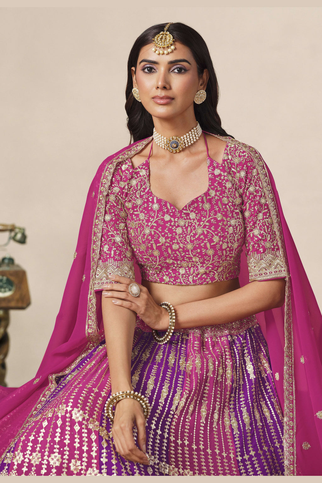 Close-up of a magenta engagement lehenga blouse in georgette with zari and sequin work on the V neckline and elbow sleeves.