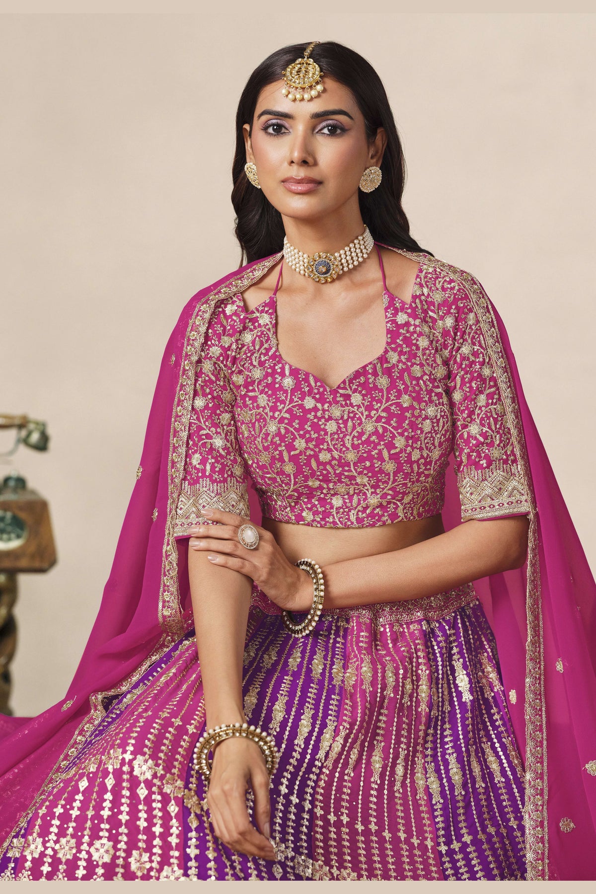 Close-up of a magenta engagement lehenga blouse in georgette with zari and sequin work on the V neckline and elbow sleeves.
