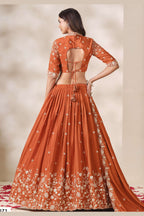 Full-length back view of a rust orange lehenga for wedding in chinon silk with an open cutout back blouse with dori tie and sequin and thread embroidery.