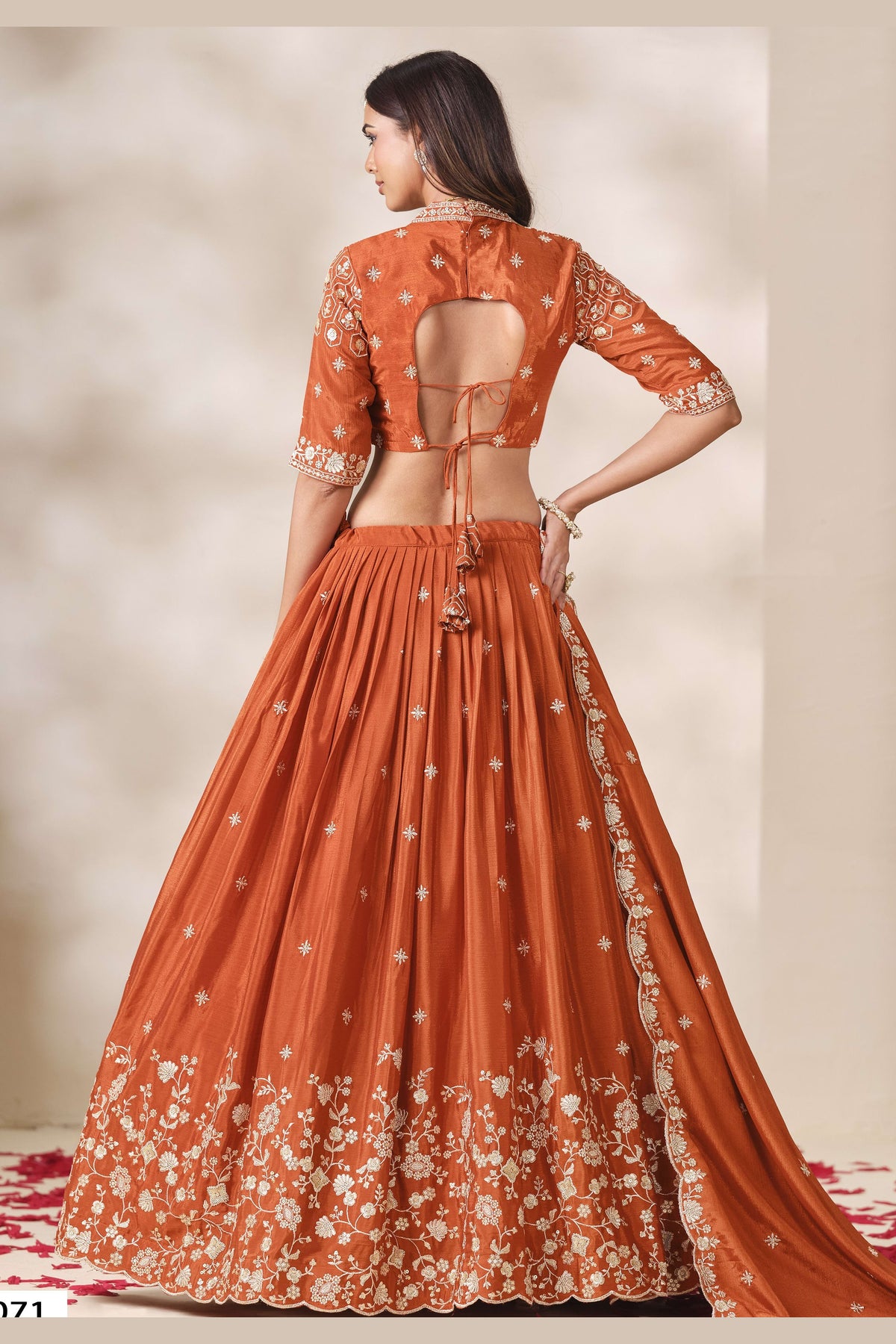 Full-length back view of a rust orange lehenga for wedding in chinon silk with an open cutout back blouse with dori tie and sequin and thread embroidery.